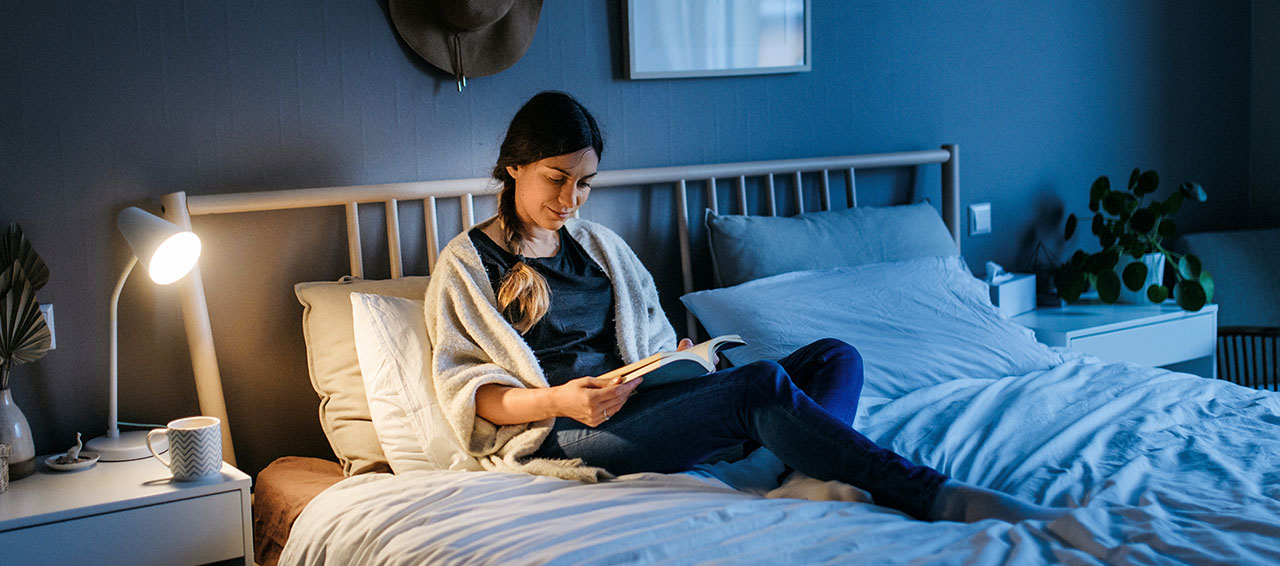 Frau liest im Bett ein Buch